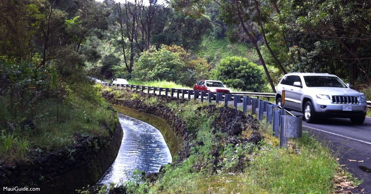 Cars traveling beside a water channel on Maui’s Road to Hāna